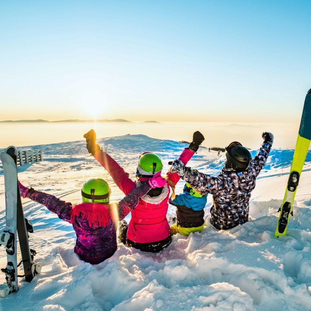 family sitting on a snowy hill with skiis